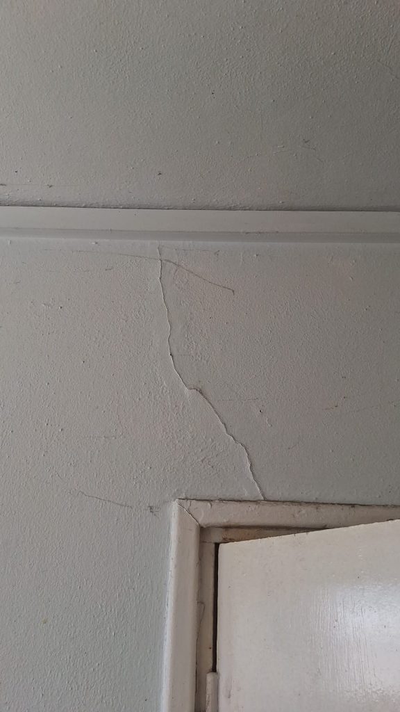 Damp and mould damage in rented property showing black mould around window frame and wall cracks